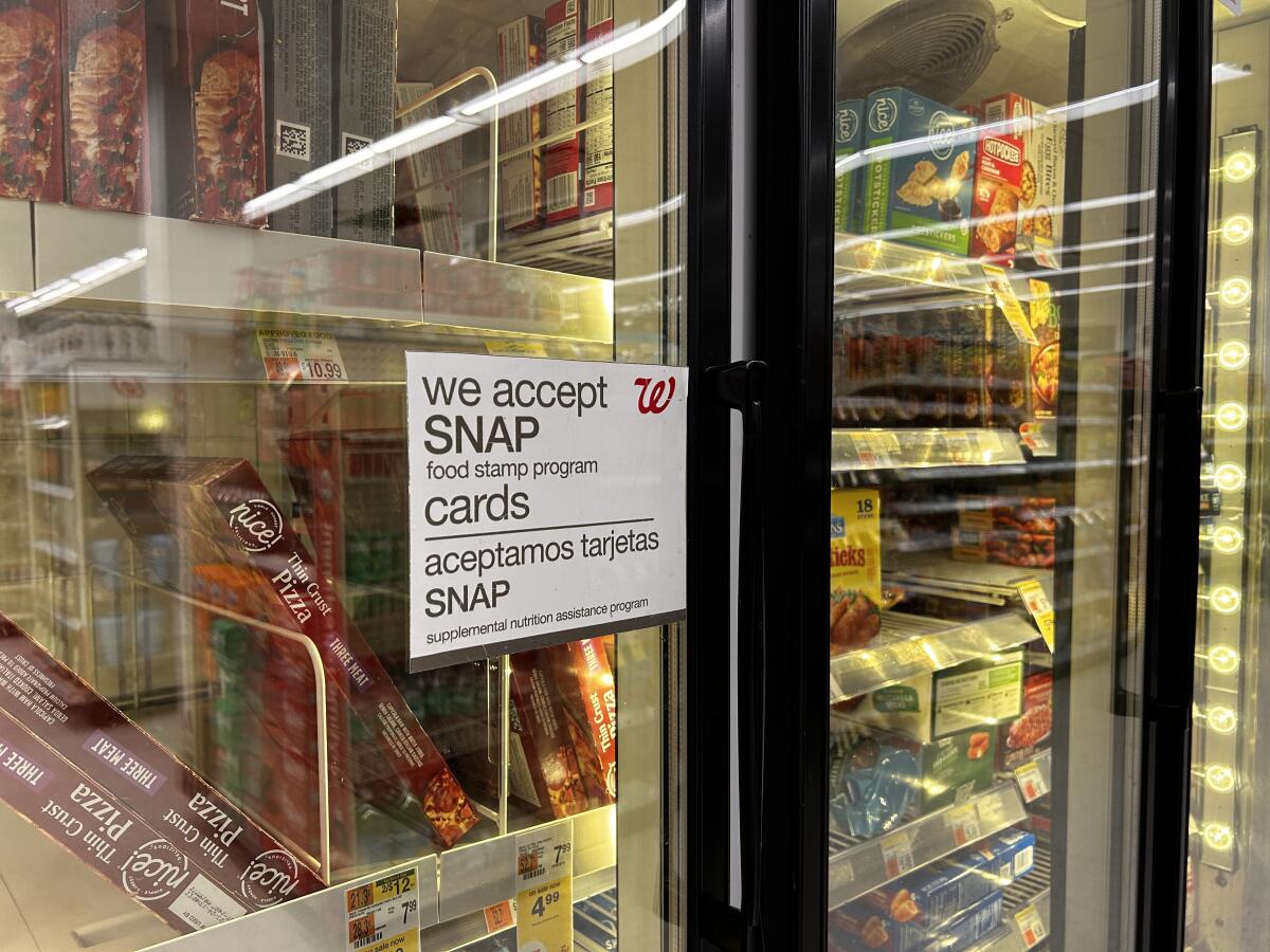 A sign in a Walgreens frozen aisle indicating the store accepts SNAP food assistance