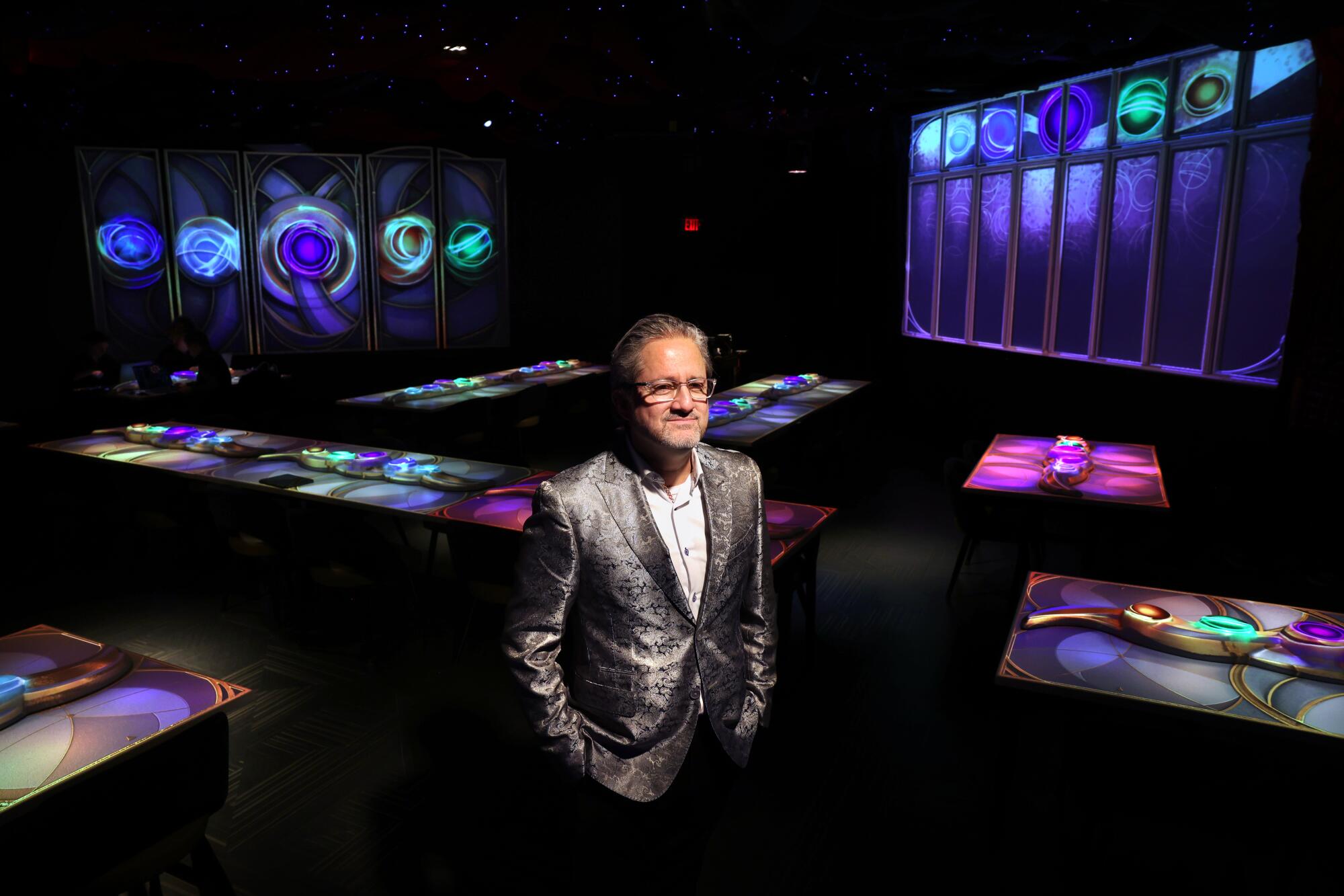 The Gallery co-founder Daren Ulmer stands among tables illuminated by projectors