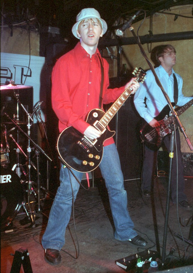 Paul Draper of Mansun performing on stage with a guitar.