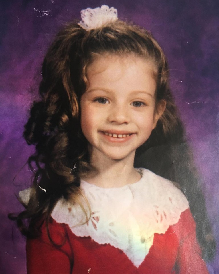 Photo of a young girl with curly brown hair in a red dress.