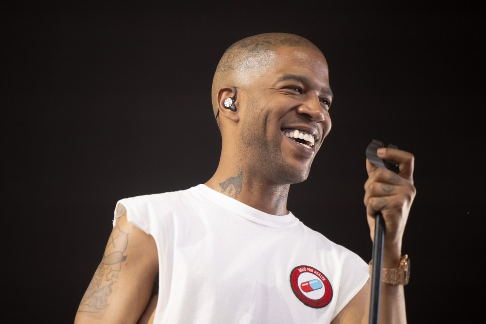 Kid Cudi smiling and performing on stage.