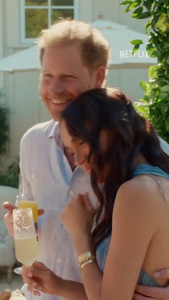 Meghan Markle and Prince Harry embracing and laughing while holding champagne flutes.