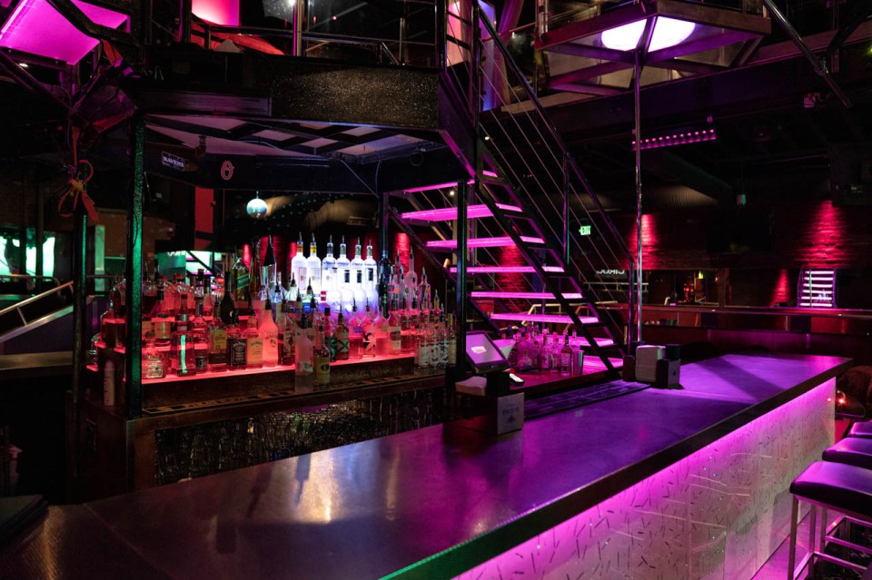 Bar with liquor bottles and a staircase in a nightclub.