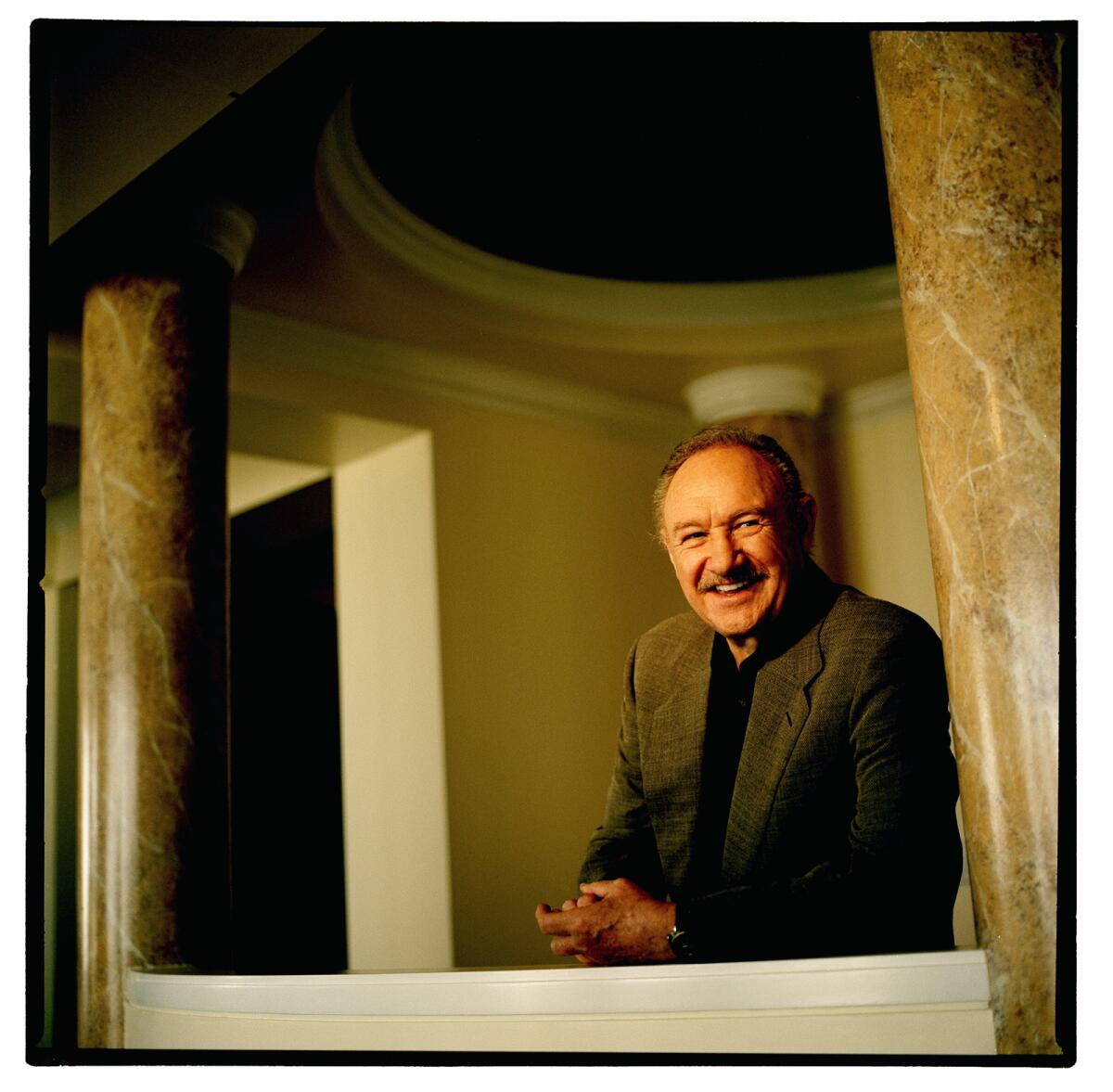 Gene Hackman rests an arm on a sill between two marble pillars.