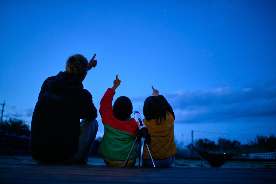 Two families stargazing with a telescope.