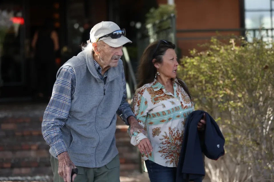 Older man with a cane walking with a woman.