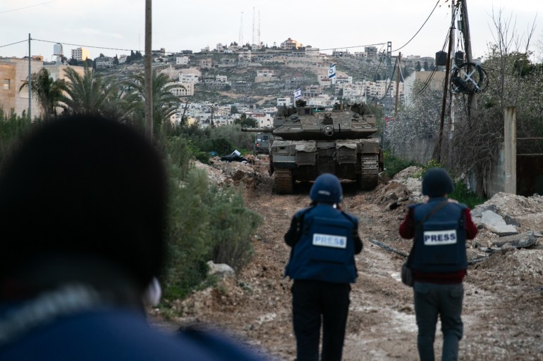 Tank in the distance with two journalists in the foreground