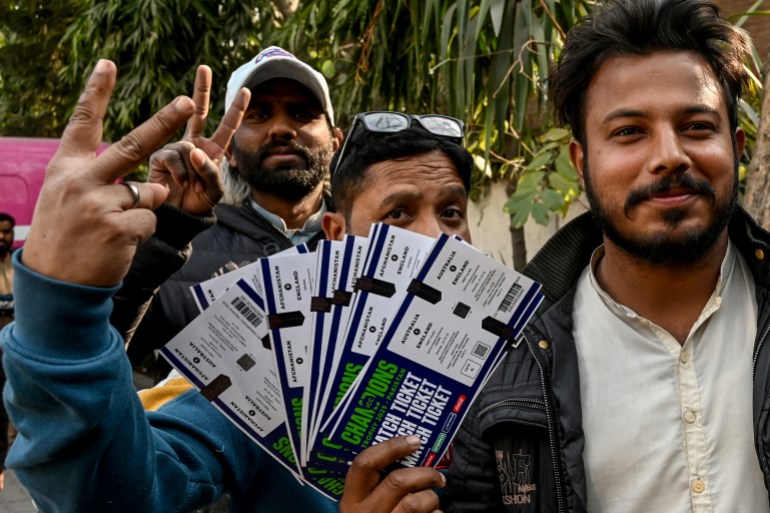 Cricket fans gesture as they show the tickets for the ICC Champions Trophy in Lahore on February 4, 2025. (Photo by Arif ALI / AFP)