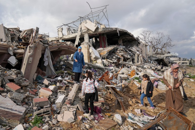 A Palestinian family stands on the rubble of their home