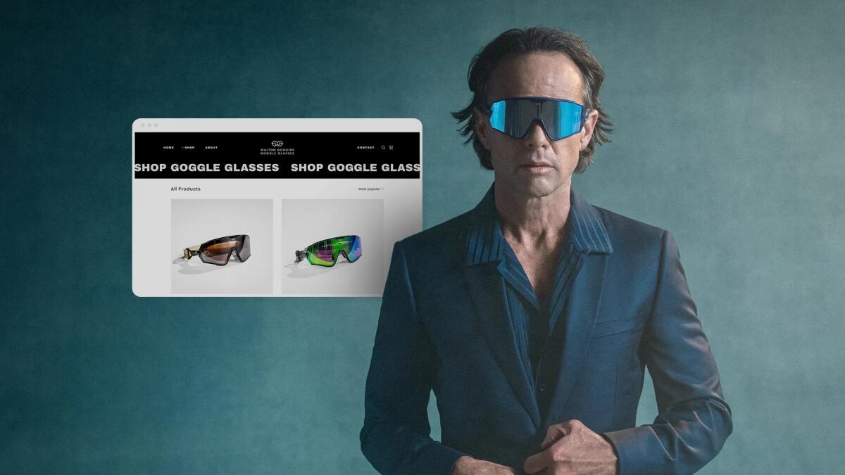 Walton Goggins wears large reflective glasses and a blue shirt and suit jacket in a TV commercial