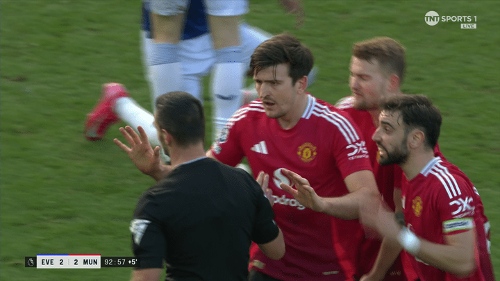 Manchester United players arguing with a referee.