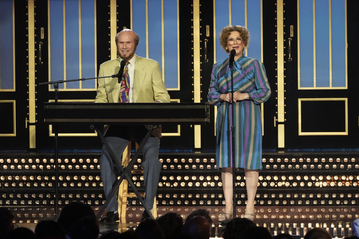 A man in a yellow blazer at a keyboard and a woman in a striped blue dress at a microphone stand.