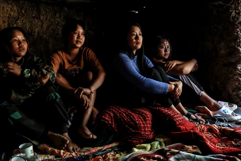 Junior, 15, who assists at a hospital camp, left, sits in a bomb shelter as a Myanmar military jet flies over in Falam township, Chin State, Myanmar, December 31, 2024.