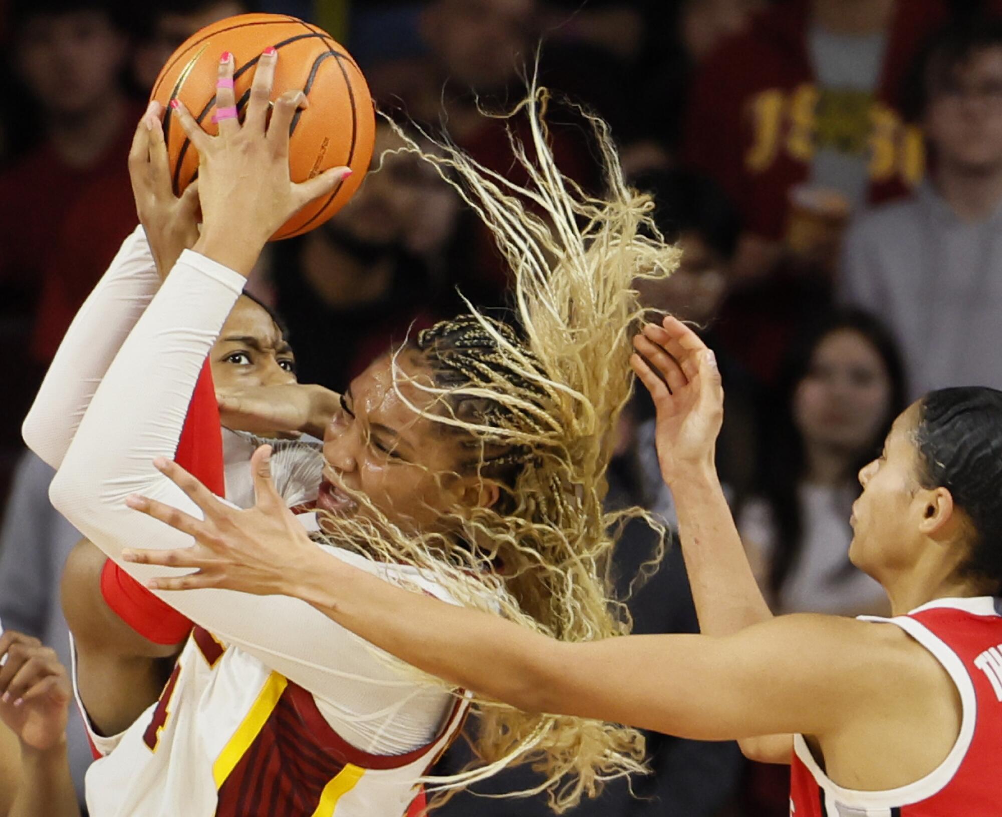 USC forward Kiki Iriafen, center, grabs a rebound over Ohio State forward Ajae Petty.