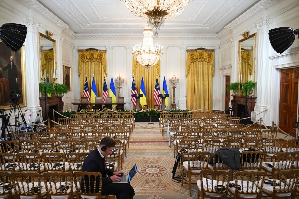 Empty chairs set up for a press conference in the East Room of the White House, with US and Ukrainian flags.