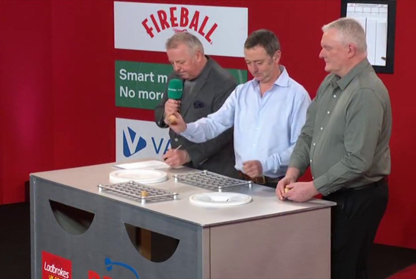 Three men participating in a game show, placing small balls into grids.