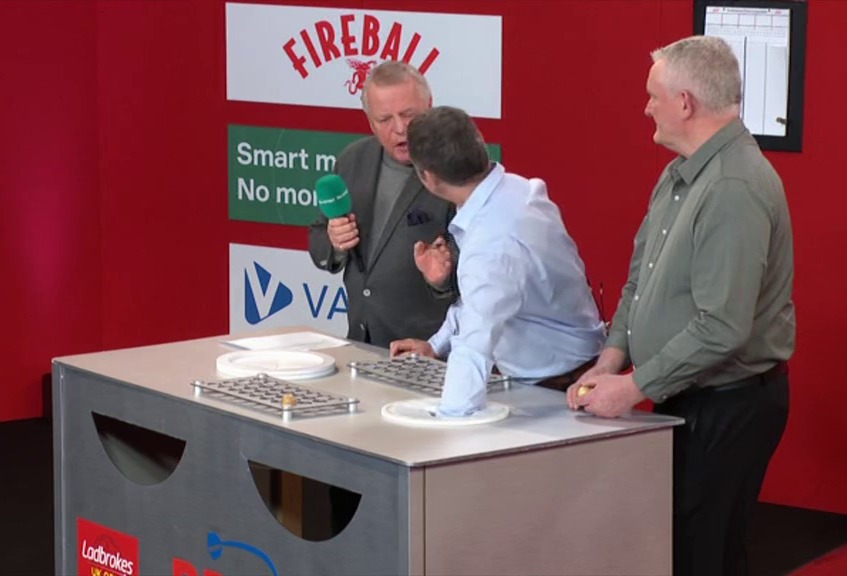 Three men at a game show table.