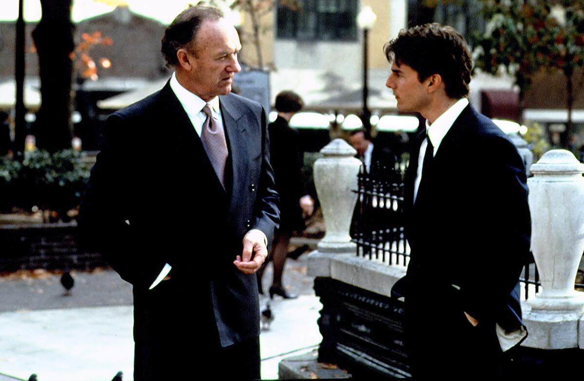 Two men in suits stand outdoors talking