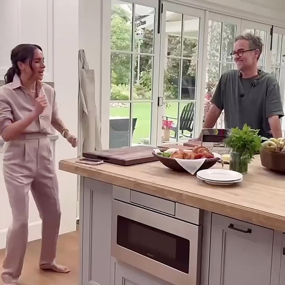 Meghan Markle and a crew member celebrating in a kitchen.