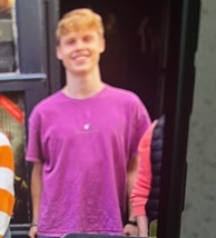 Young man smiling in purple t-shirt.