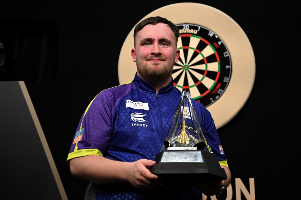 Luke Littler holding a Premier League Darts trophy.