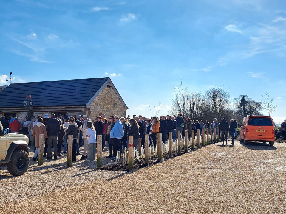 Long queue of people outside a farm shop.