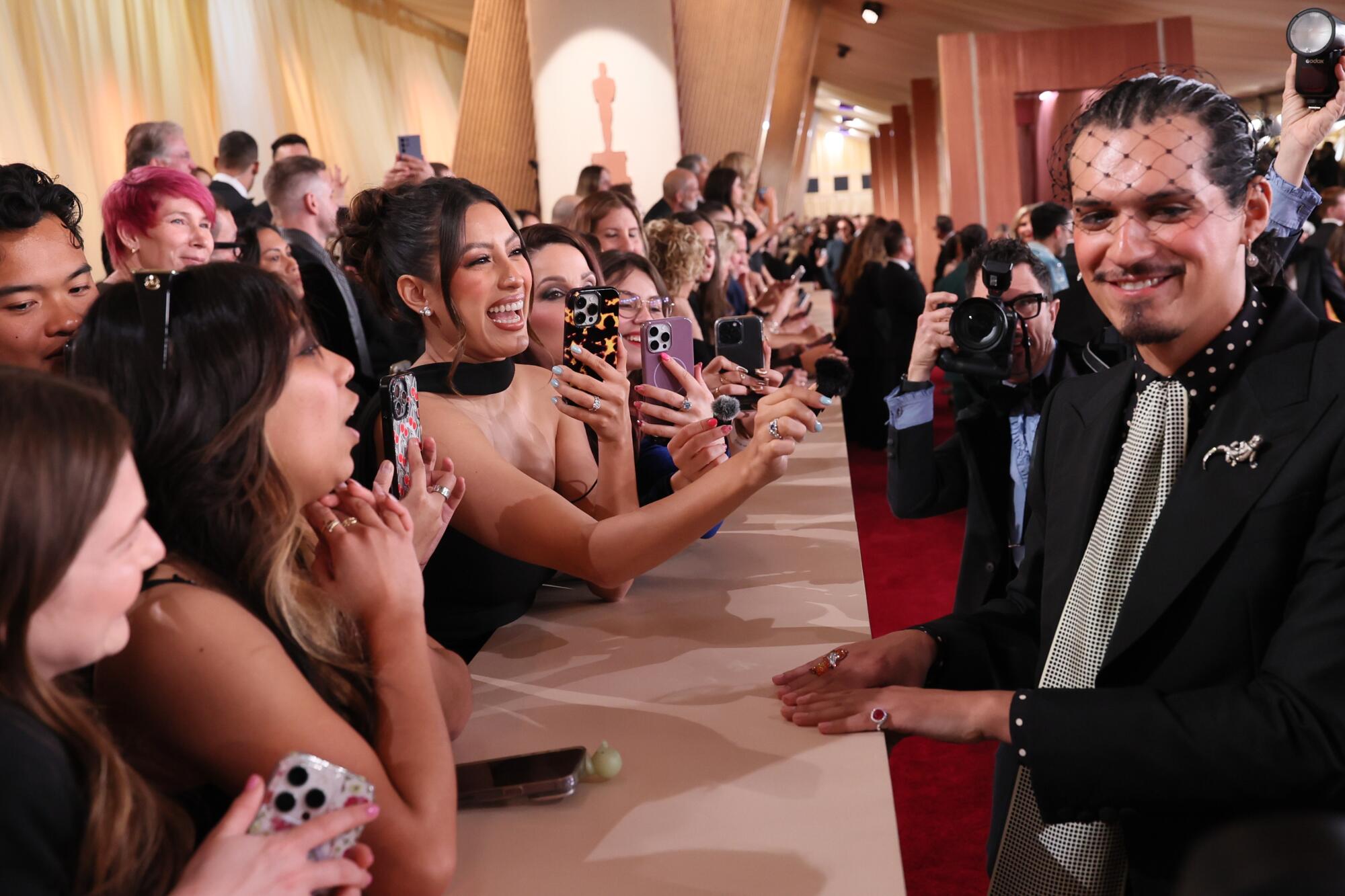 People hold up phones toward a man.