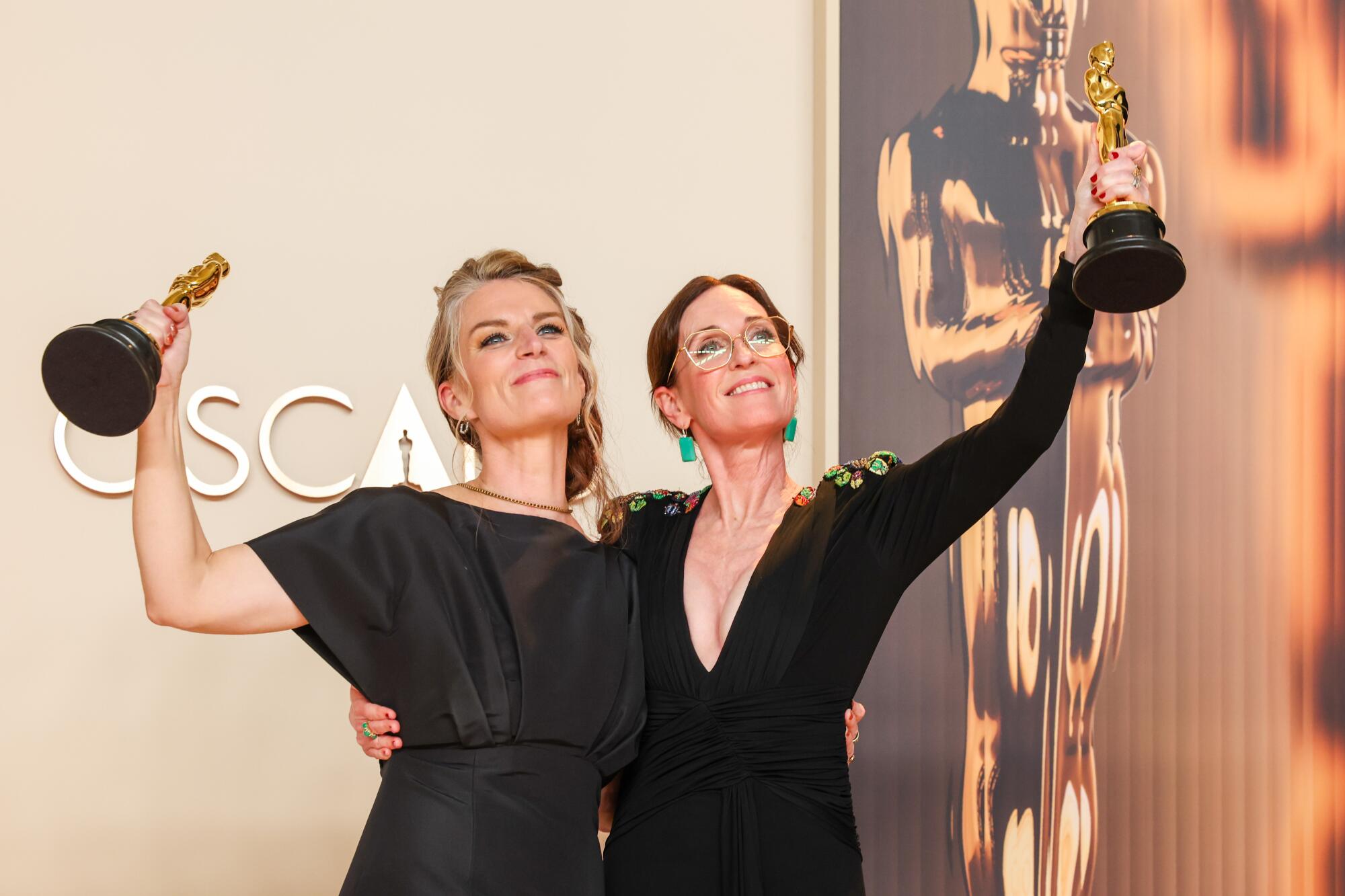 Two women raise statuettes.