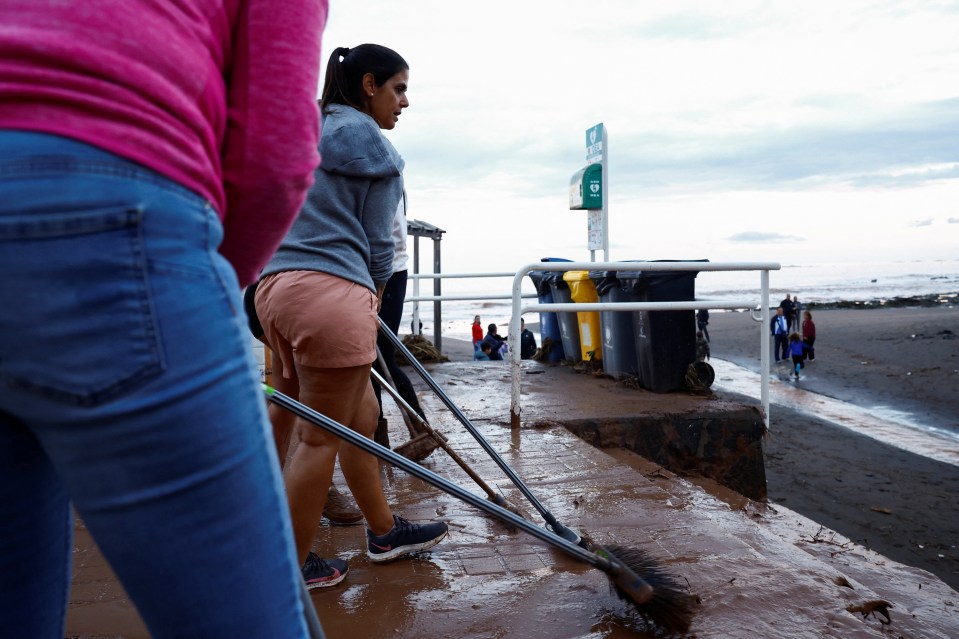 People cleaning mud from a walkway after a heavy rain.