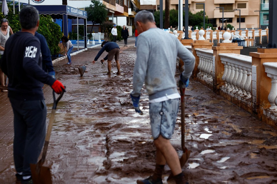 People cleaning mud from a street after heavy rain.