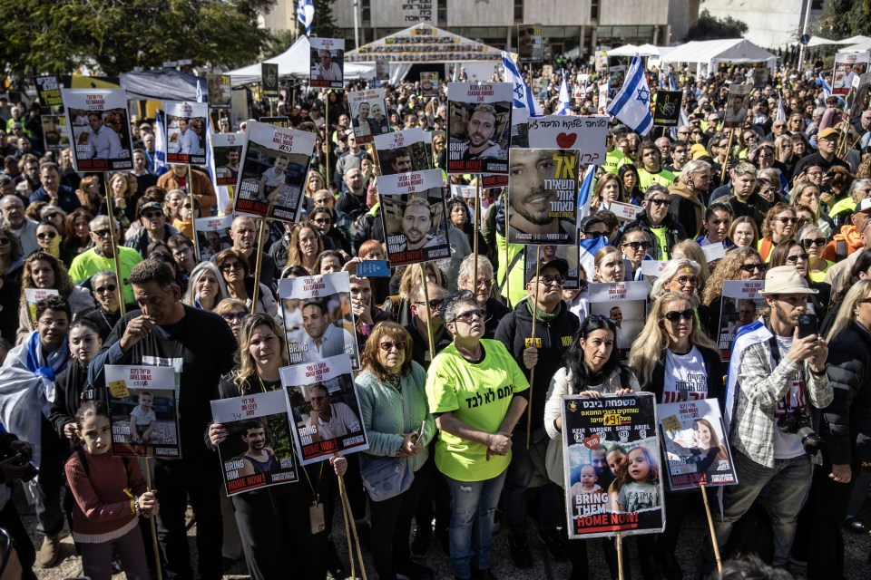 Israelis holding signs with photos of hostages and Israeli flags, demanding their release.