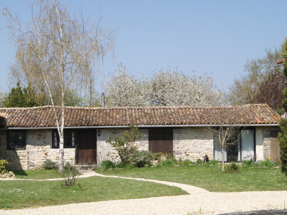 Stone house with brown door and tile roof.