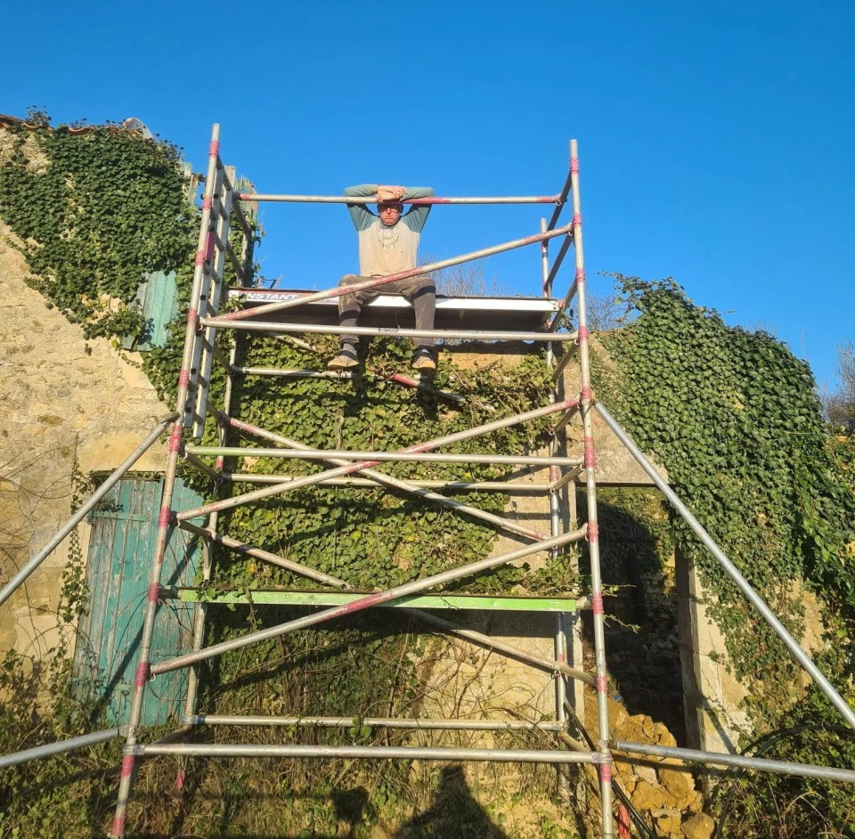 Man sitting on scaffolding during house renovation.