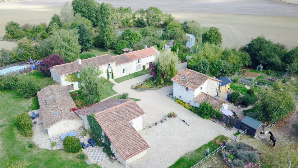 Aerial view of a French hamlet with several houses, a pool, and a garden.