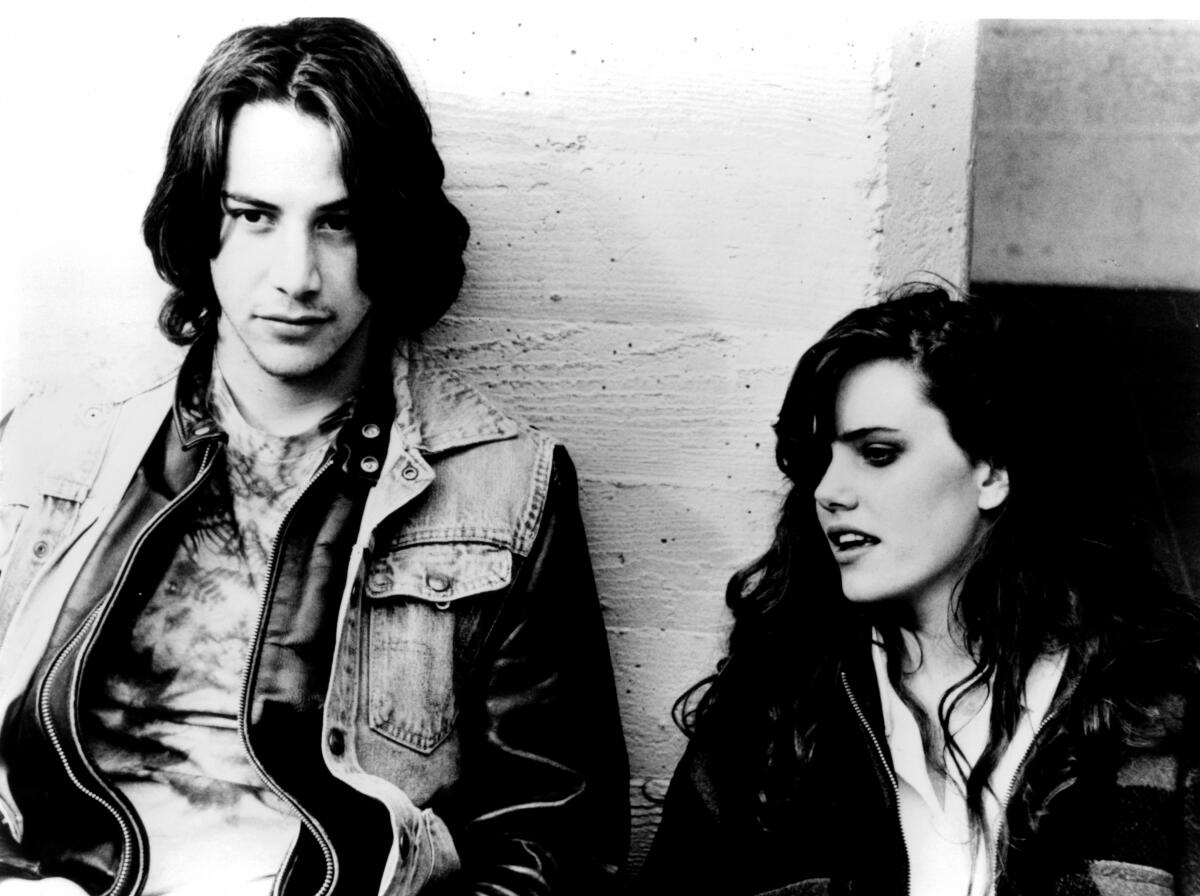 Keanu Reeves and Ione Skye stand against a wall in a scene from "River's Edge."