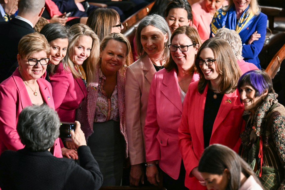 Female Democratic members of Congress in pink jackets protesting administration policies.