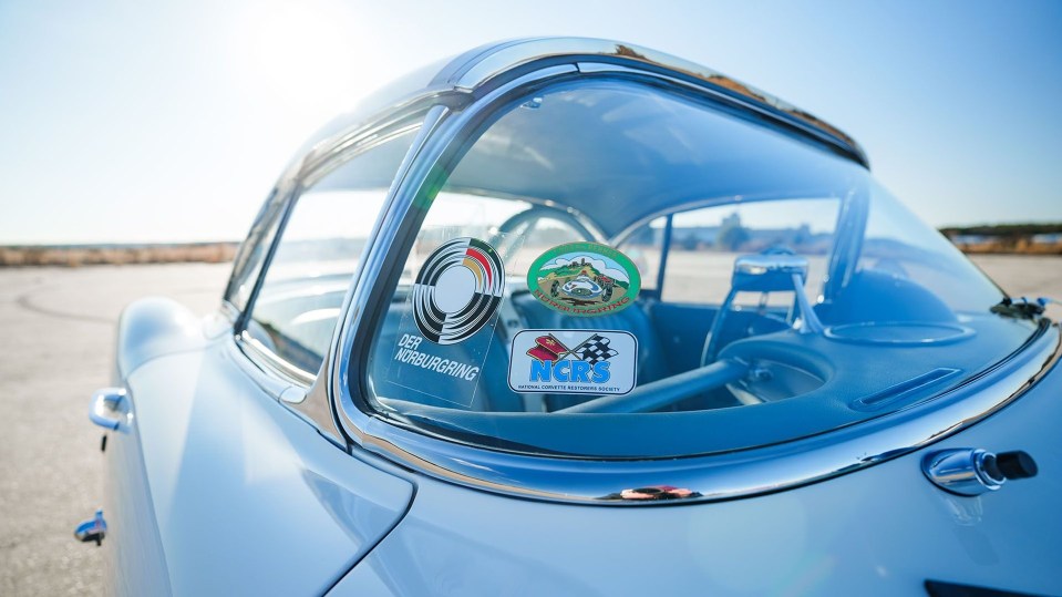 Close-up of a restored 1960 Chevrolet Corvette's windshield with Nürburgring and National Corvette Restorers Society stickers.