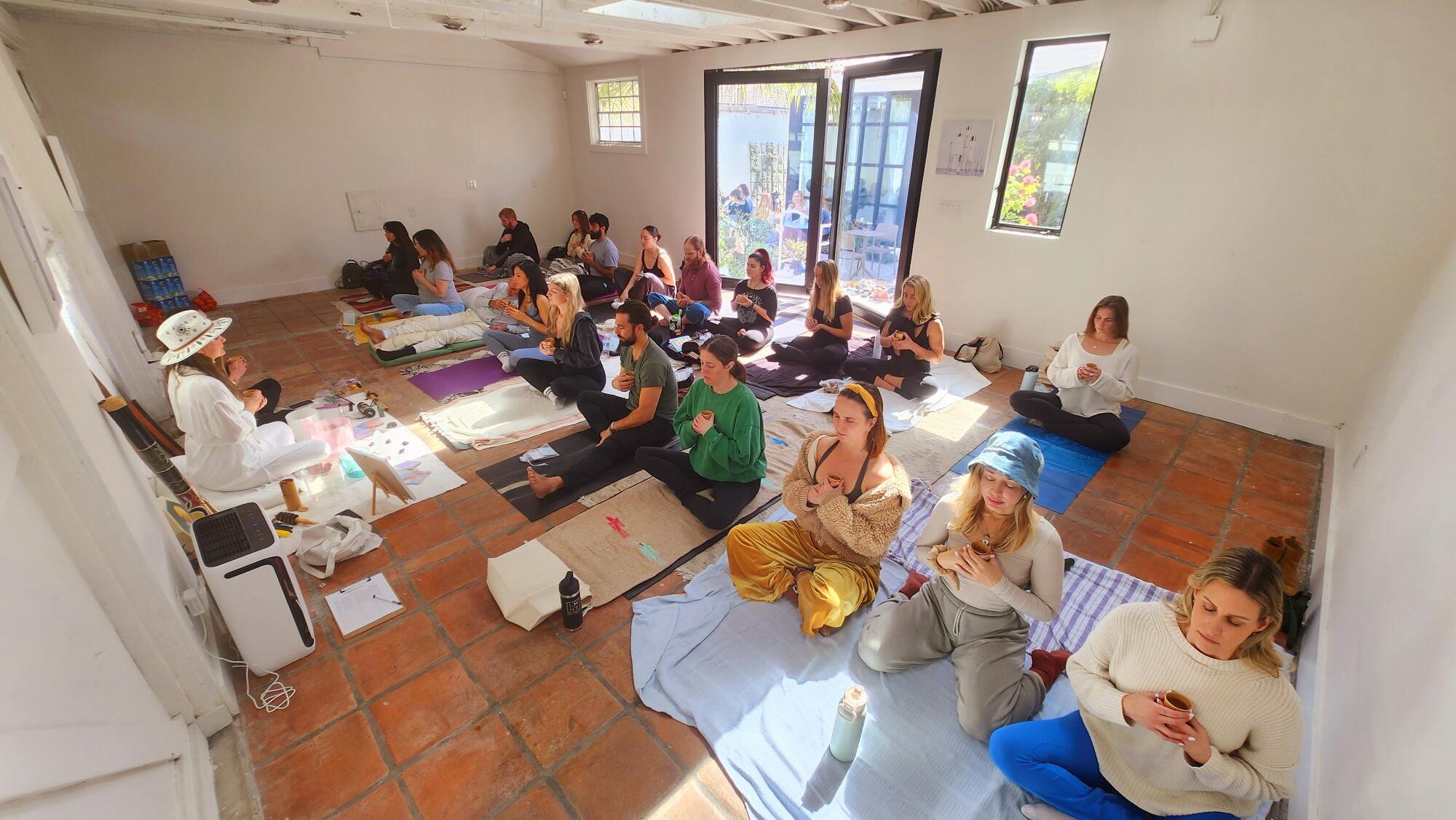 People sit on a studio floor holding cups.