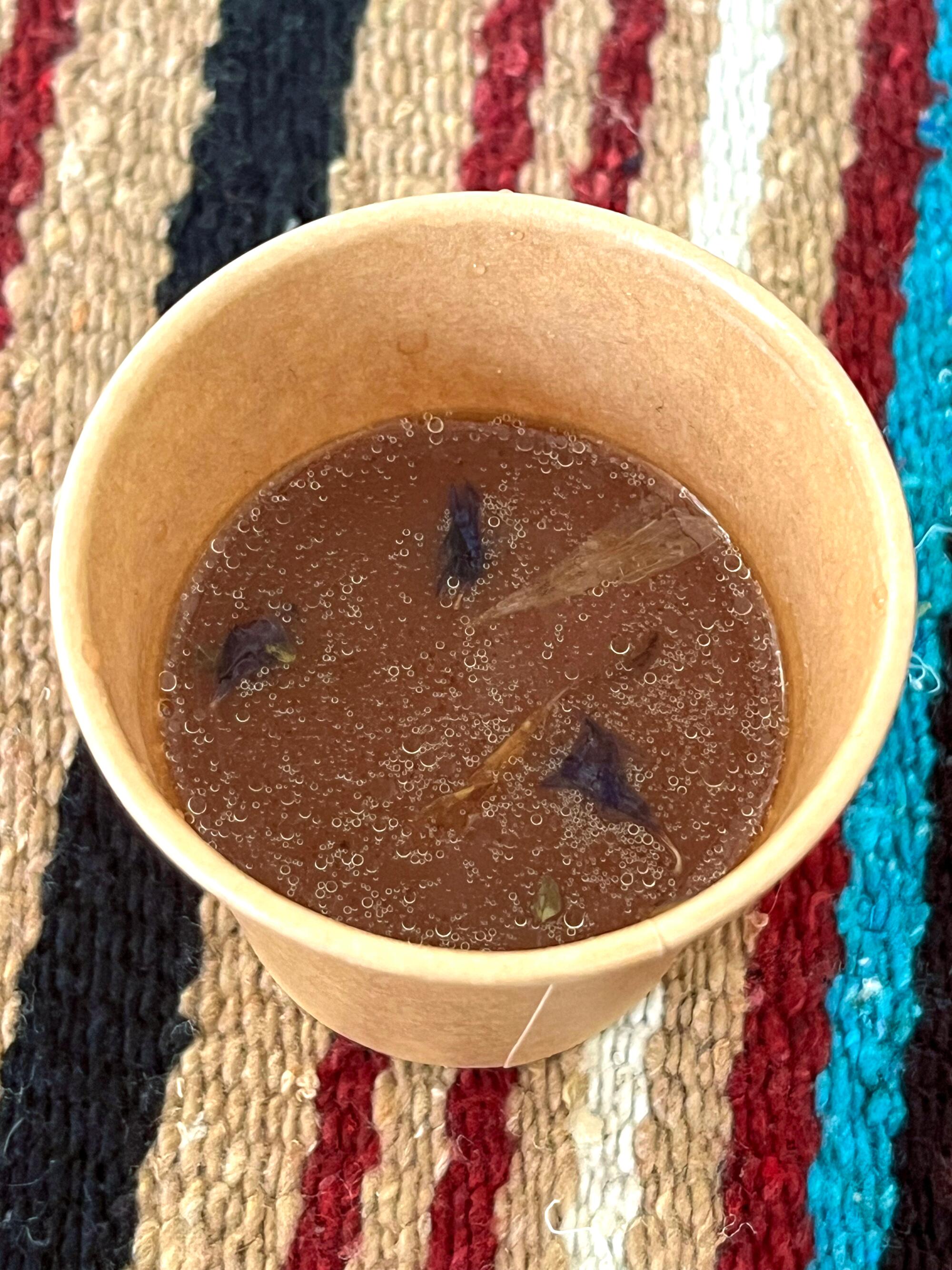 Small edible flowers float on the surface of a cup of cacao.