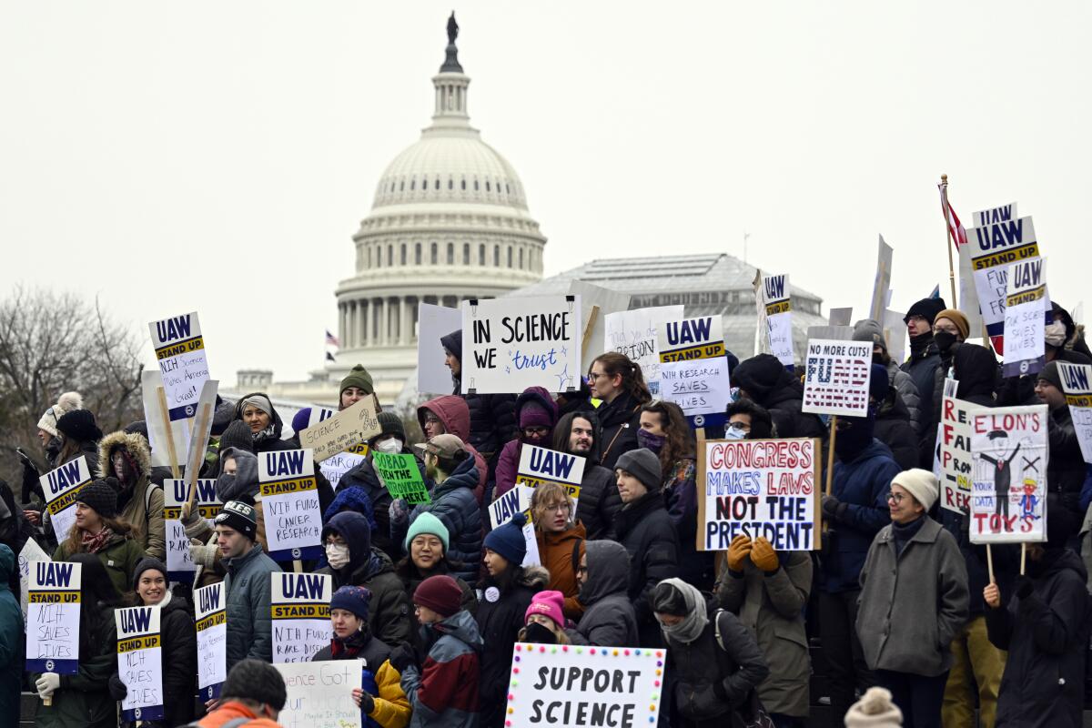 Protesters with signs reading "Support science" with the U.S. Capitol in the background.