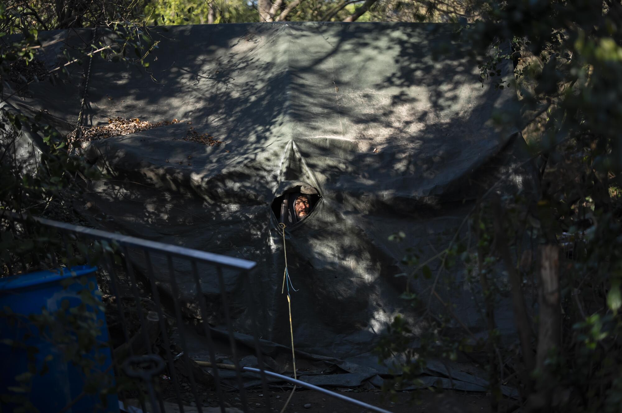 A man peers through a hole in his tent.