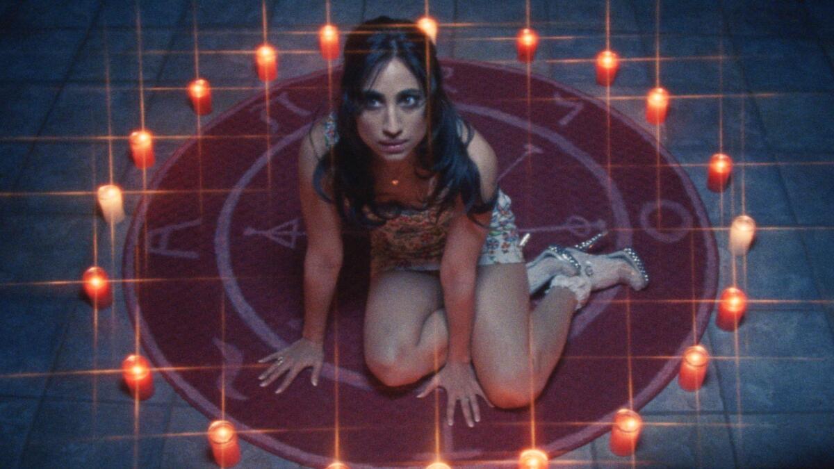 A woman sits on the floor in a circle of candles.