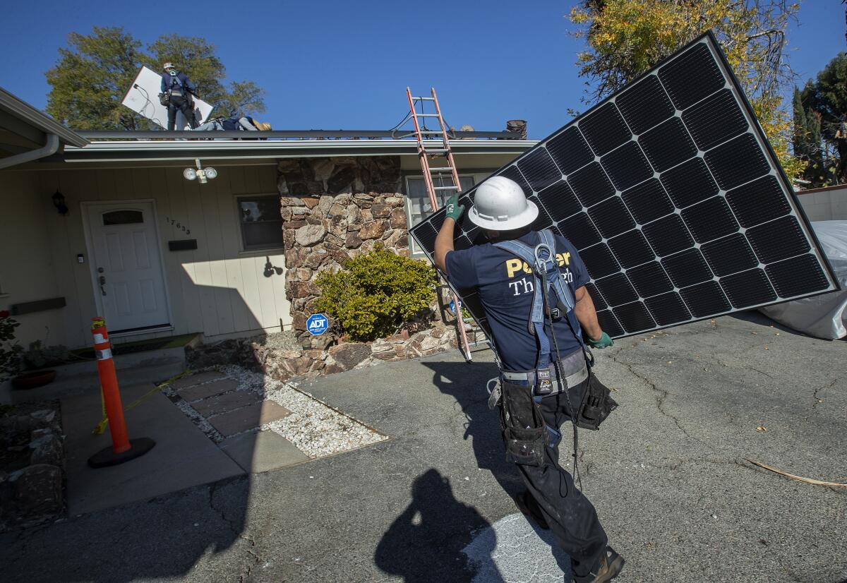 A Sunrun employee carries a solar panel