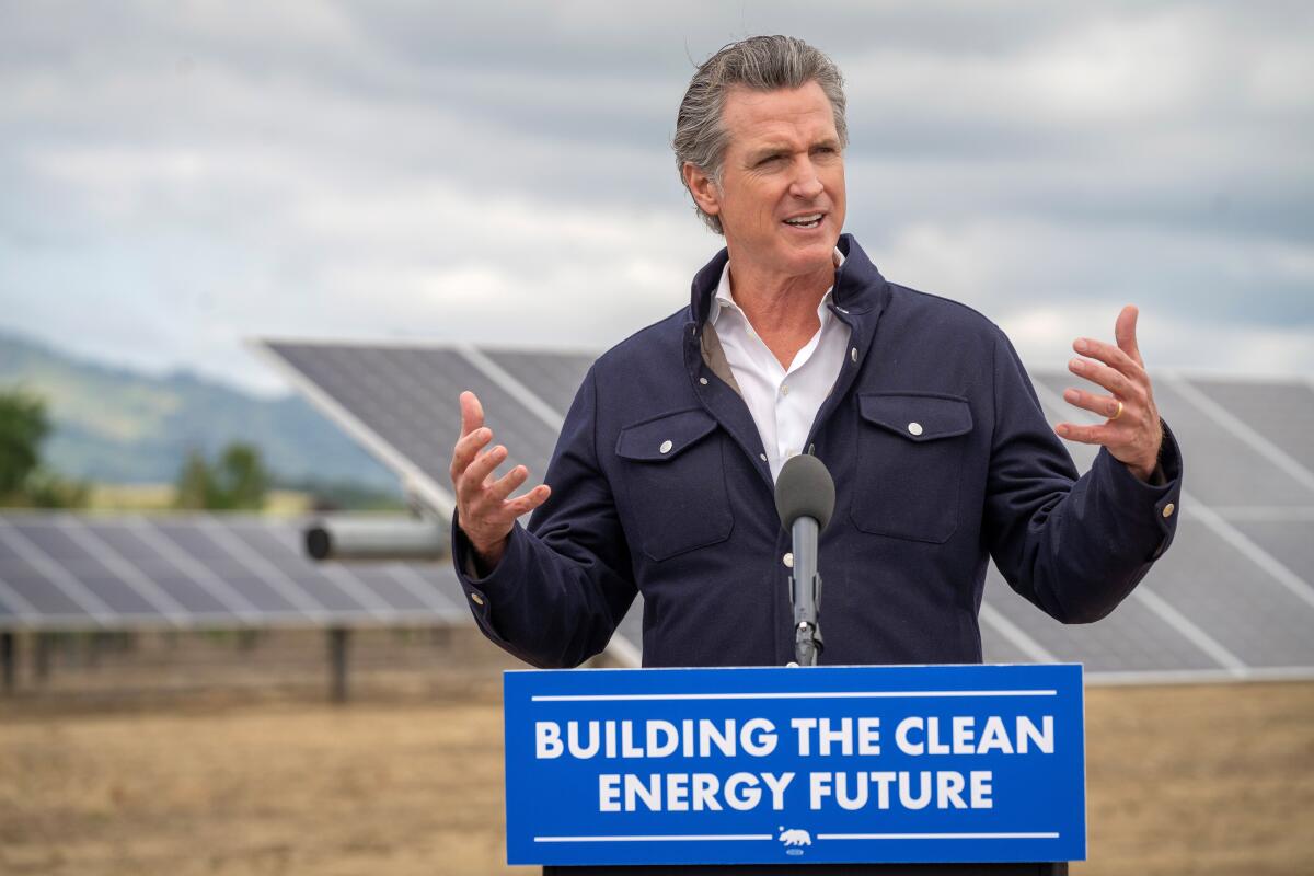 Gov. Gavin Newsom speaks at a lectern, with solar panels in the background