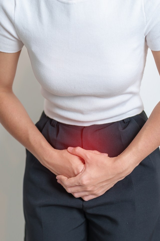 a woman in a white shirt and black pants holds her hands on her stomach