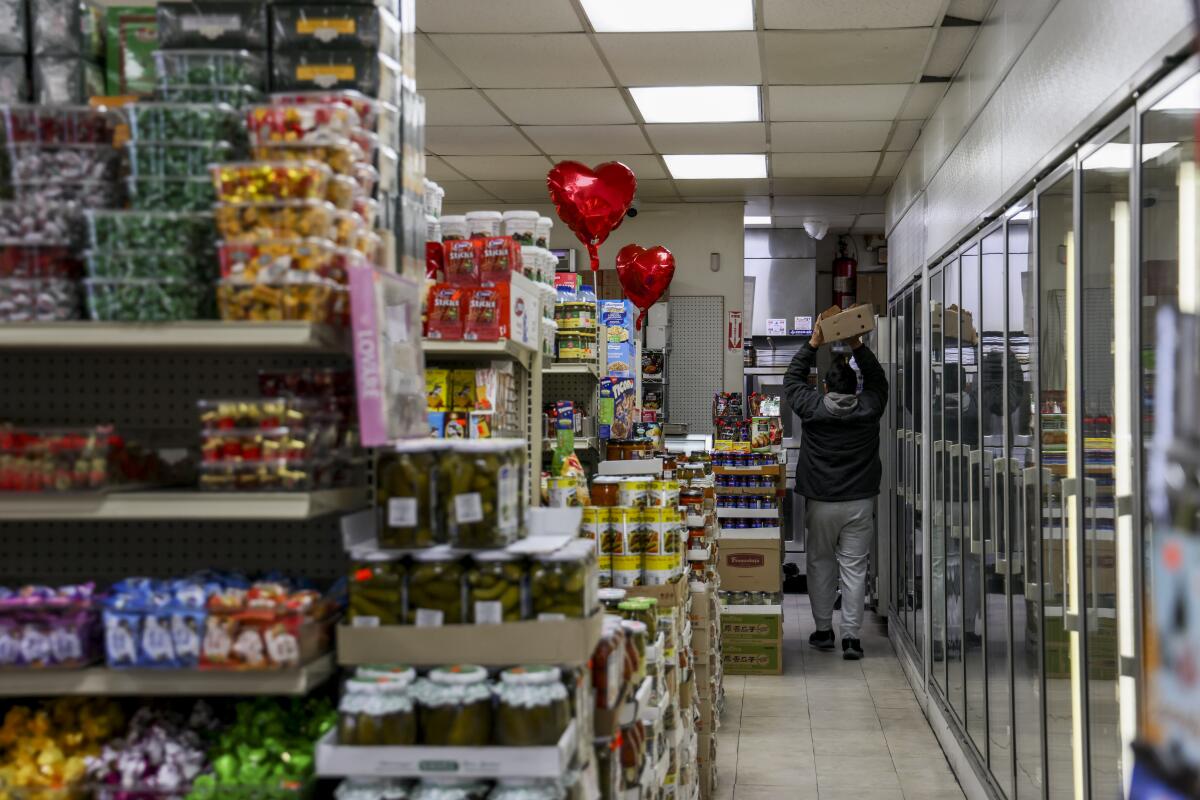 A worker carries boxes to the back of Odessa Grocery on March 5 in Valley Village.
