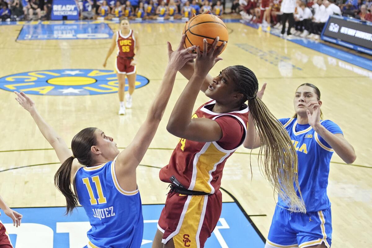 USC center Clarice Akunwafo, center, shoots over UCLA guard Gabriela Jaquez