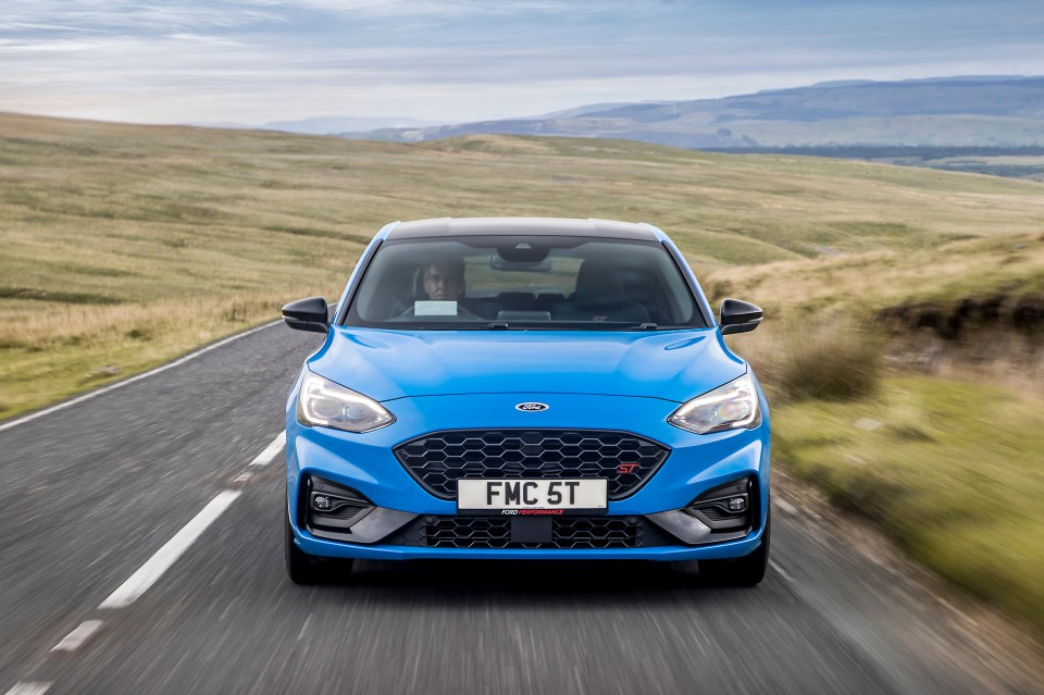 Blue Ford Focus ST driving on a country road.