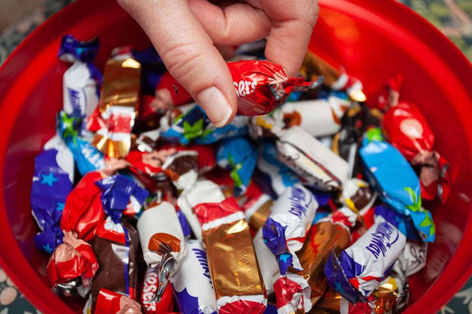 Hand reaching for a Celebrations chocolate from a bowl of assorted chocolates.