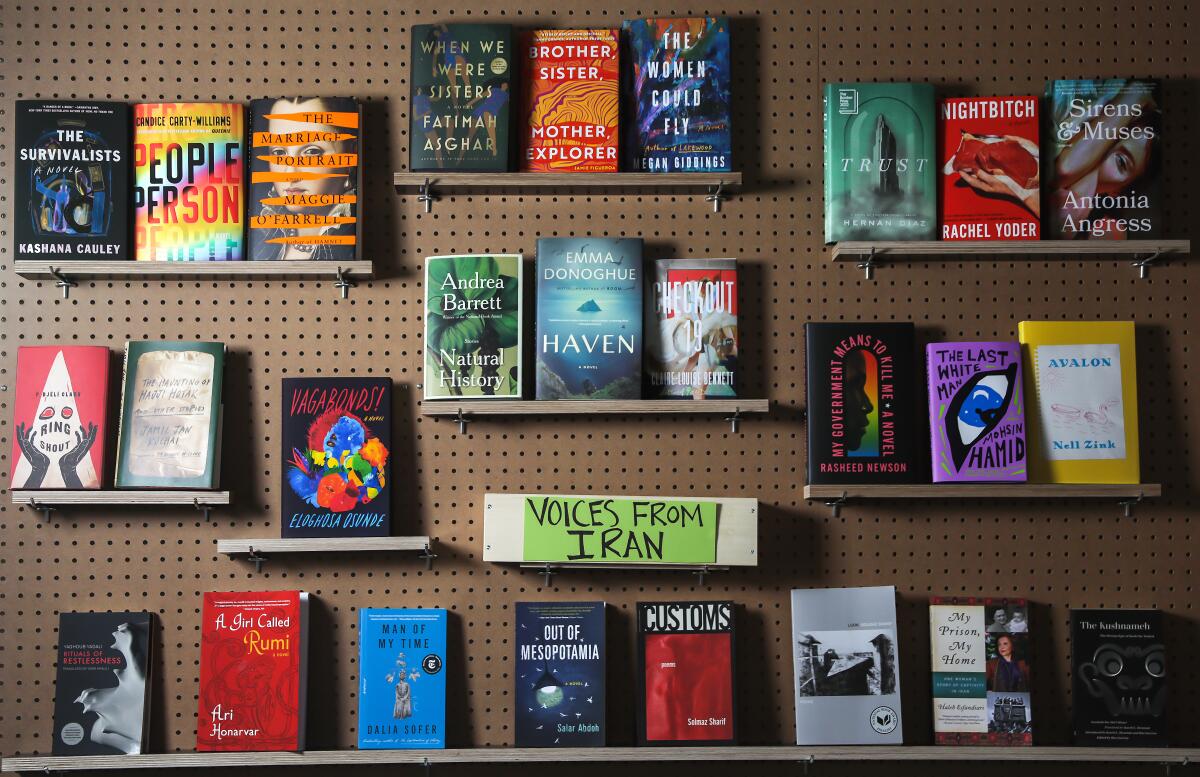 Books on shelves against a wall, their covers facing out 